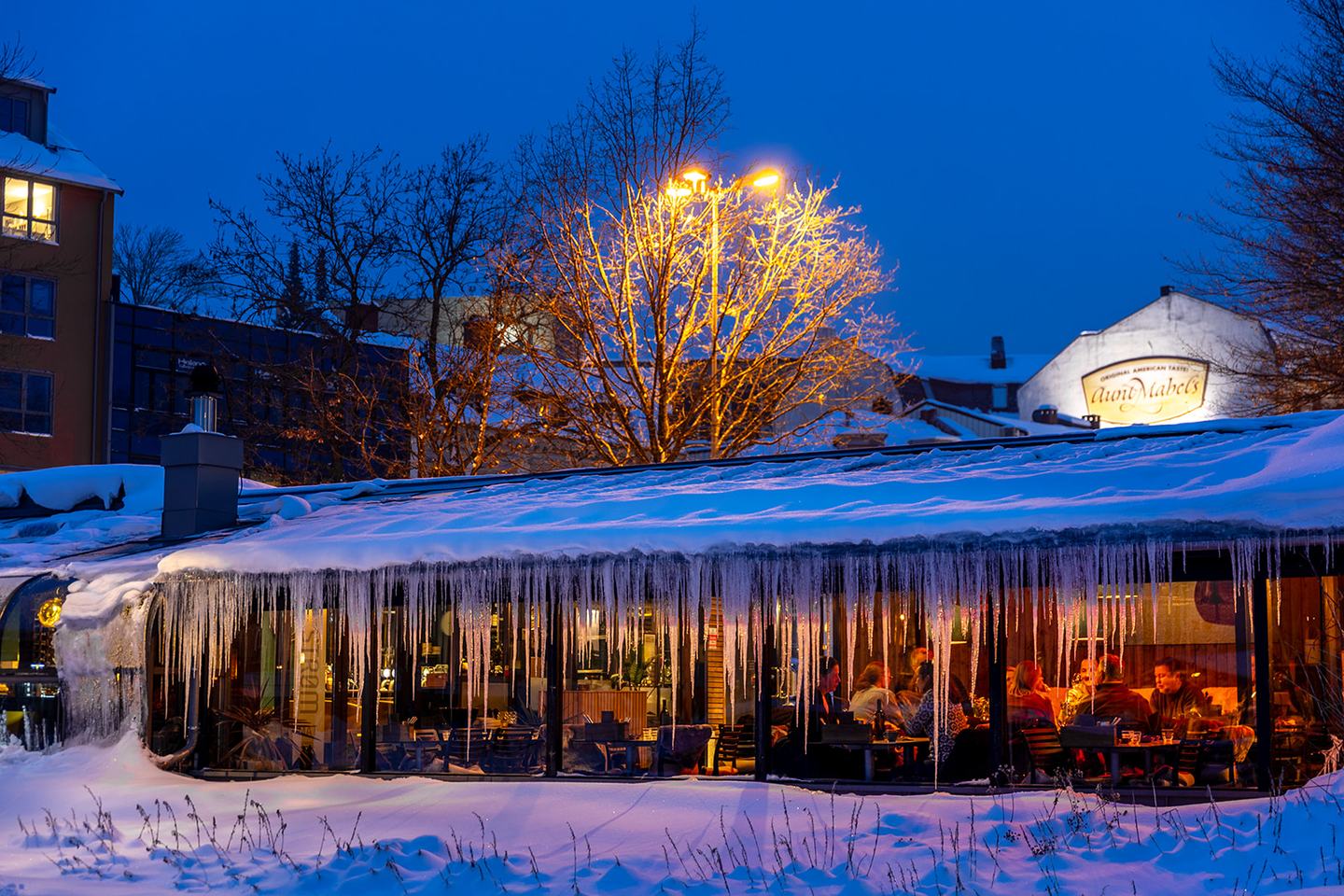 Restauranten i blåtimen, med snø og istapper på taket og varme opplyste vinduer der gjester sitter inne